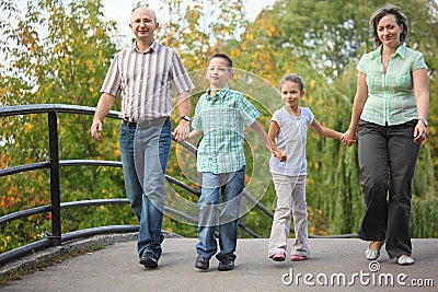 Family walking on bridge in early fall park