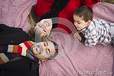 Family in Winter Clothing Laying on Their Backs in Park