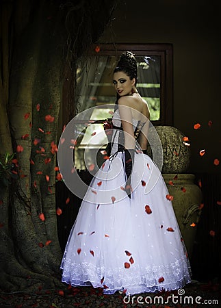 Fantasy bride surrounded by red rose petals