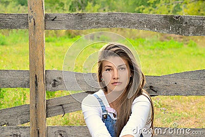 Farm Girl Standing Next To Old Wooden Fence