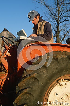 Farmer on tractor working on laptop computer