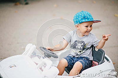 Fashion little boy driving toy car in a park