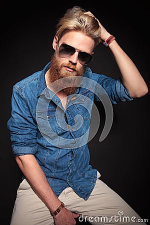 Fashion man in blue shirt sitting and fixing his hair