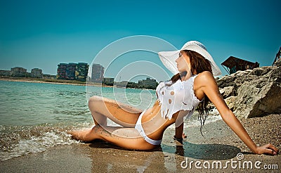 Fashion portrait of young sexy brunette girl in bikini and wet t-shirt at the beach