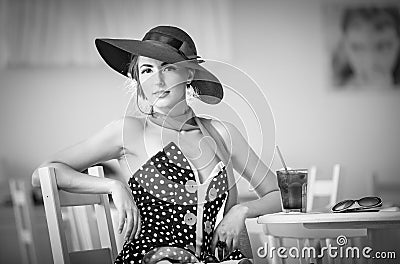 Fashionable attractive lady with hat and scarf sitting in restaurant