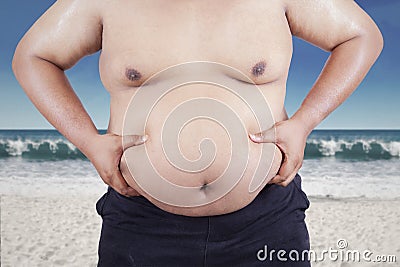 Fat man holding his stomach at beach