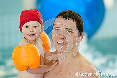 Father with baby in swimming pool are making fun