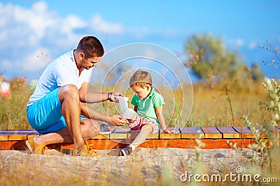 Father bandaging injured leg of kid