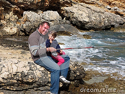 Father and daughter fishing on sea on summer day
