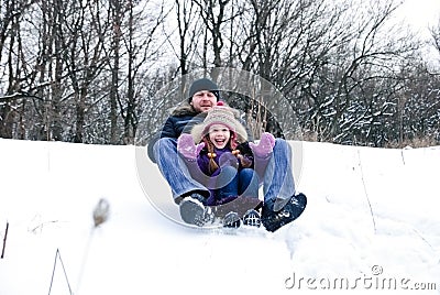 Father and daughter riding on a sledge