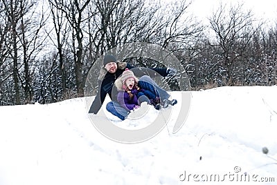 Father and daughter riding on a sledge