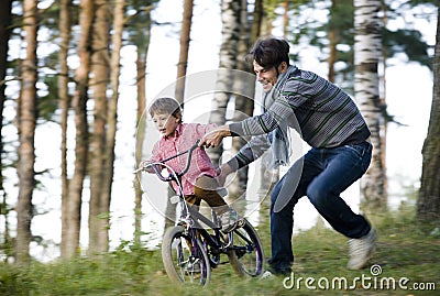 Father learning his son to ride on bicycle outside