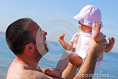 Father lifting his baby daughter on the beach