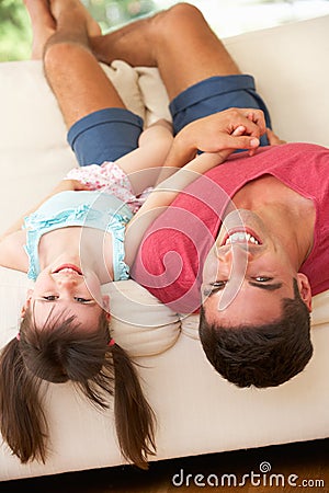 Father Lying Upside Down On Sofa With Daughter