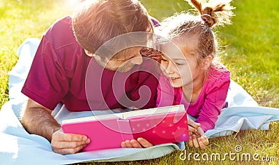 Father reading a book to his daughter in the garden