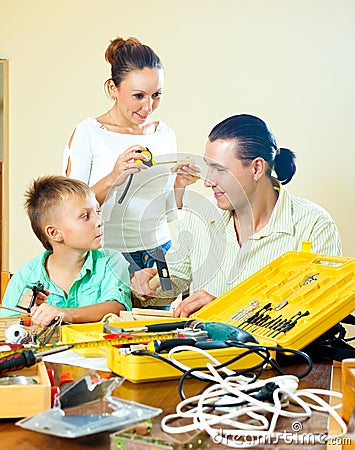 Father and son crafting with working tools, happy woman watching