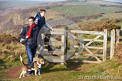 Father And Son With Dog Walking Along Coastal Path