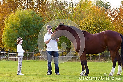 Father and son feeding a horse on a autumn day