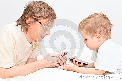 Father and son with mobile phones at home