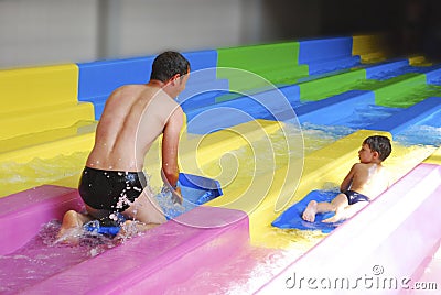 Father and son riding in the water park with slides.