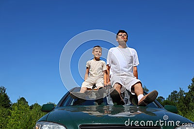 Father with son sit on roof of car in day-time