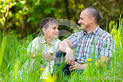 Father and son sitting in grass