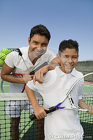 Father and son standing at net on tennis court portrait