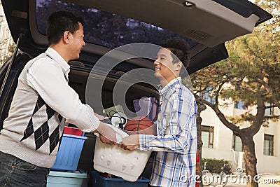 Father and son unpacking car for college