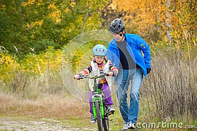 Father teaching child to ride bike