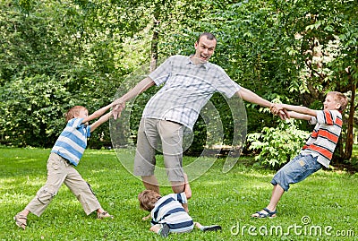 Father and three sons play in the park.