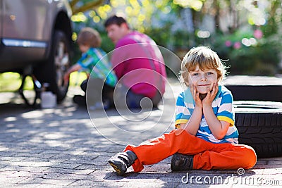 Father and two little boys repairing car and changing wheel toge