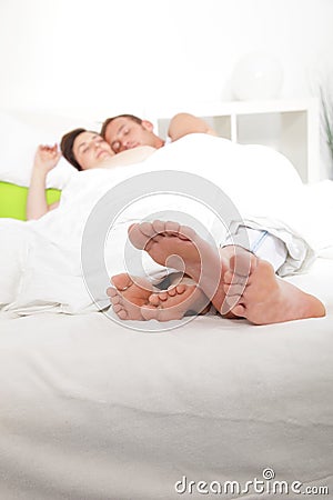 Feet of a young couple sleeping in bed