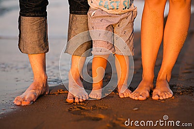 Feet of a young family on a sea beach