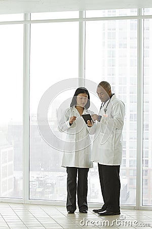 Female Asian doctor with African American doctor with tablet