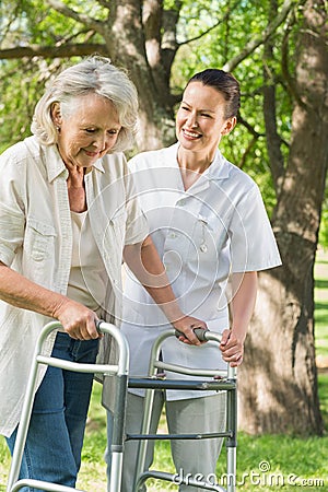 Female assisting mature woman with walker at park