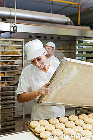 Female baker baking bread rolls