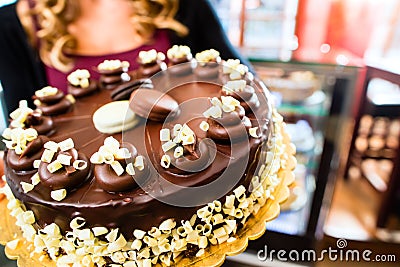 Female baker presenting cake in confectionery