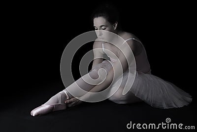 Female dancer sit on floor looking sad in pink tutu low key