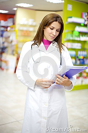 Female doctor with documents inside pharmacy