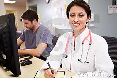 Female Doctor With Male Nurse Working At Nurses Station