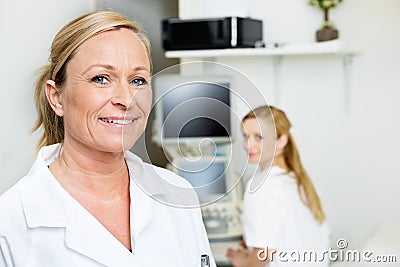 Female Doctor Smiling With Colleague In Background