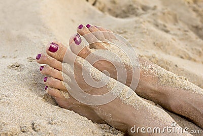 Female feet on the beach covered in sand