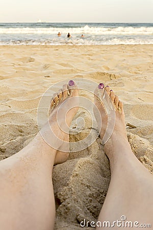 Female feet on the beach woman watching ocean