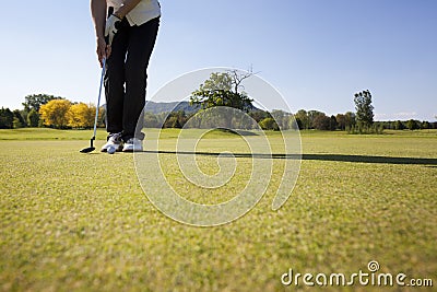 Female golf player putting ball.