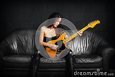 Female guitarist sitting on a leather couch