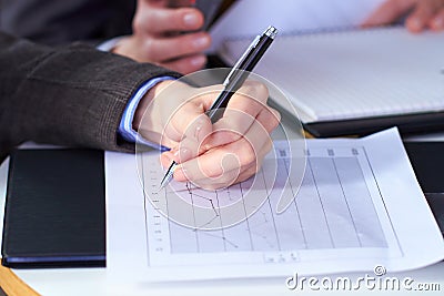 Female hand holds pen over graph