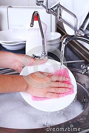 Female hand with a sponge washing dish