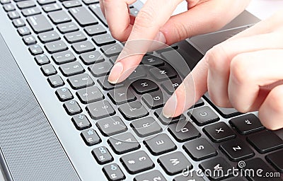 Female hand writing on a laptop keyboard