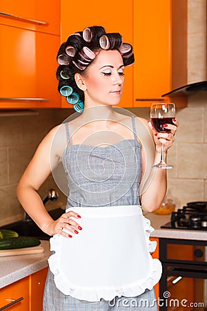 Female middle-aged housewife in the kitchen with glass of wine