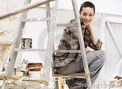 Female Painter Sitting On Ladder In Work Site